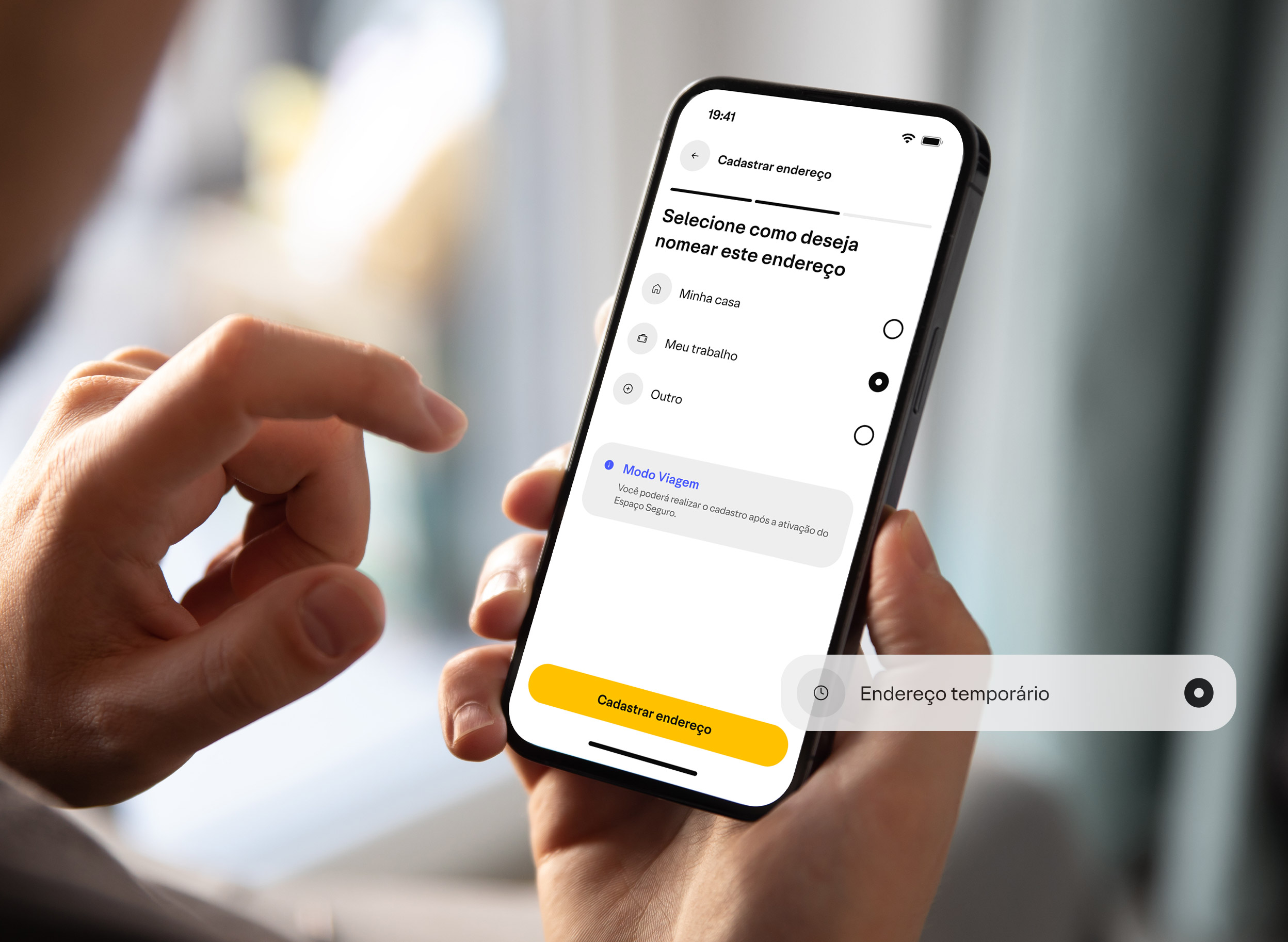 Vista por cima do ombro uma pessoa segurando um celular e na tela mostra o aplicativo xp
